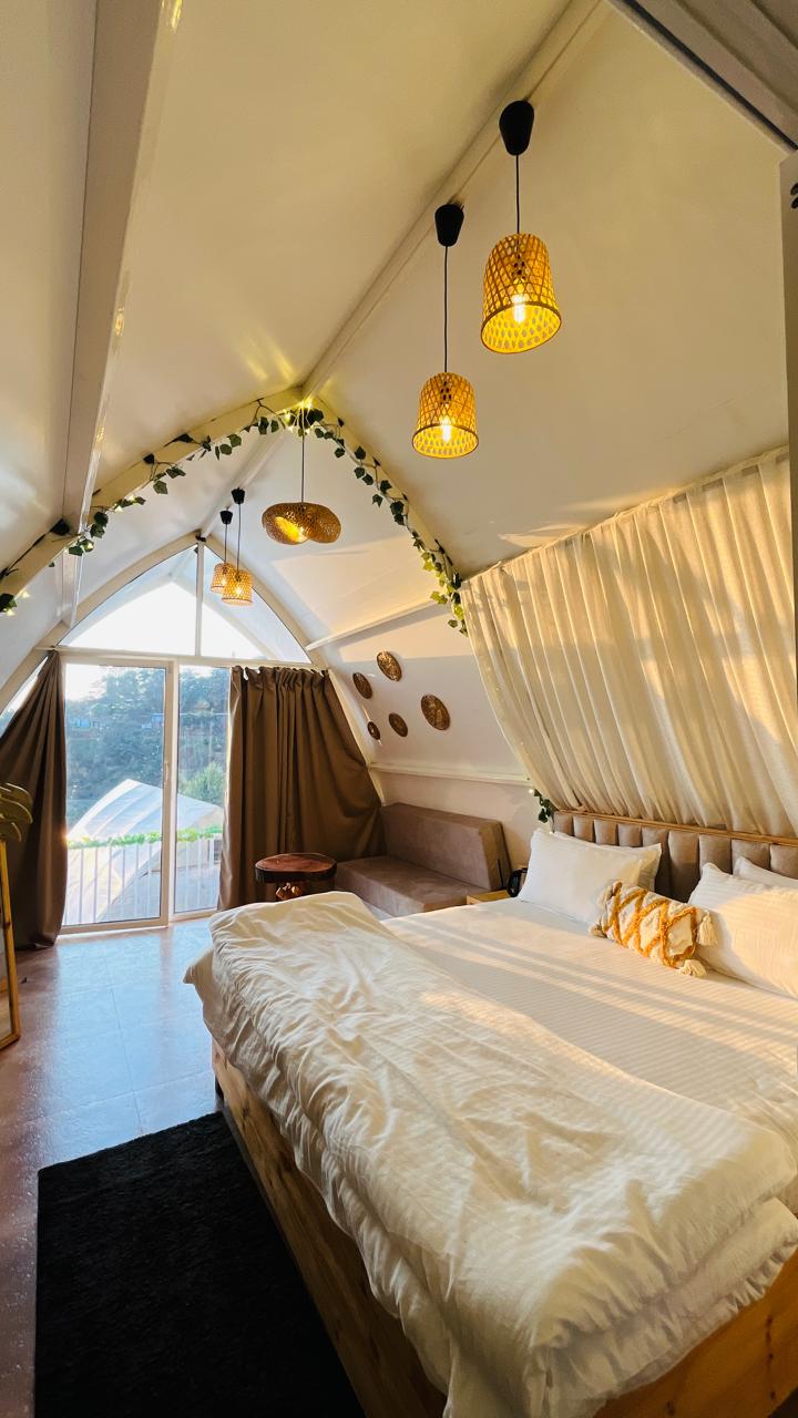 Cottage bed beside a lake-facing glass door in daylight
